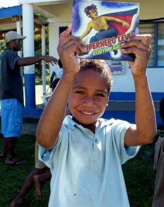 A boy from Conua District School holds up his favourite book, Superhero Levi! donated by...