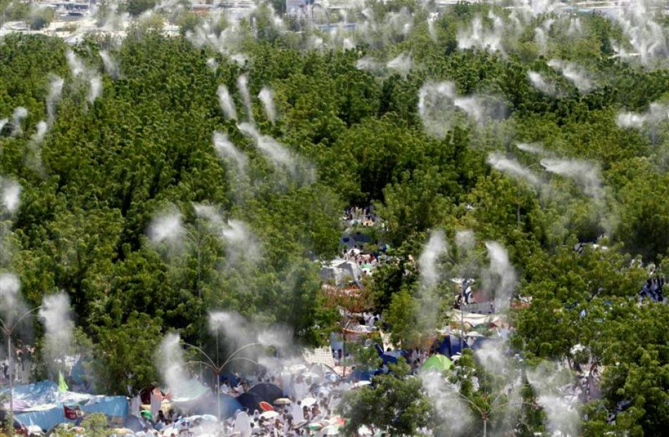 Water is sprayed over Muslim pilgrims as they pray outside Namira mosque in Arafat near Mecca,...