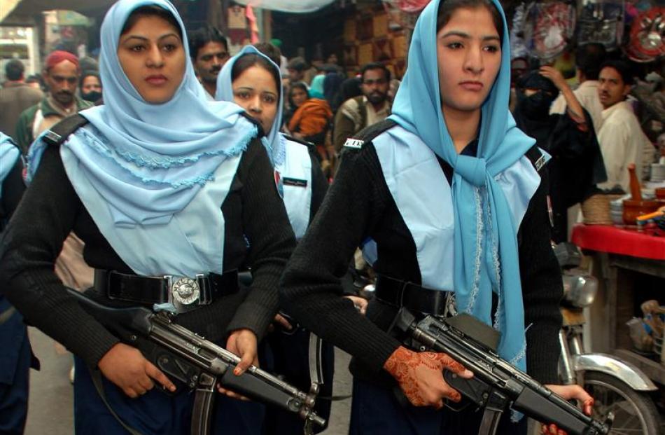 Pakistani female police officers patrol the street as people are seen in a market ahead of the...