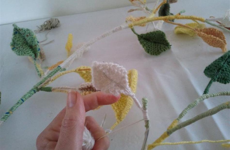 Juliette Laird attaches the knitted leaves to the branches.