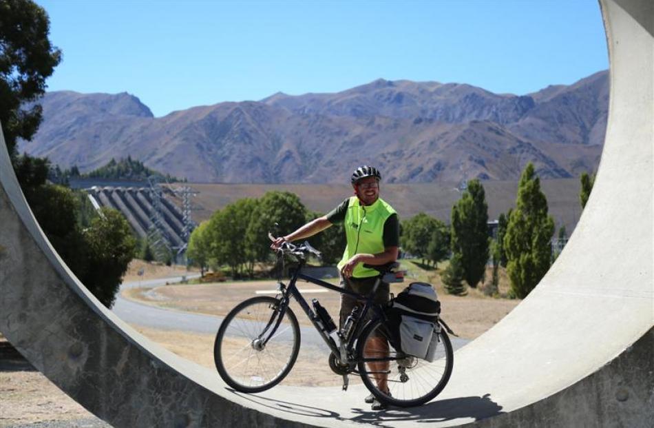 A cyclist poses for a photo along the Alps 2 Ocean cycle trail by Benmore Dam near Otematata.