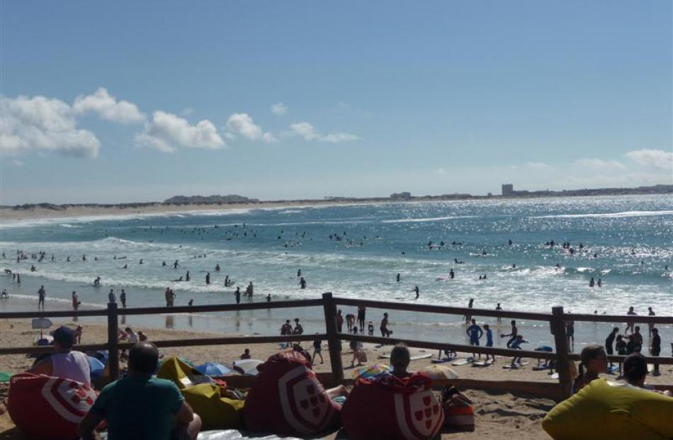 Beachgoers watch  surfers at Baleal Beach near Peniche. Photos by Alex Vilel.