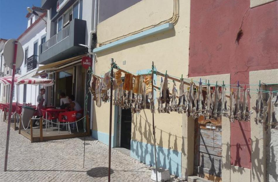 Fish hangs out to dry on a cobblestone street in Peniche.