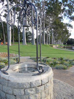 A wishing well is flanked by pockets of wildflowers and rows of eucalyptus trees at King's Park...