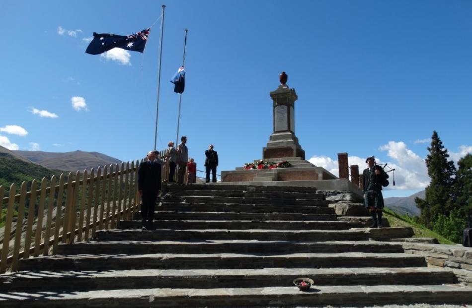 Flags are lowered to half mast at the Arrowtown War Memorial while bugler Martin Wightman, of...