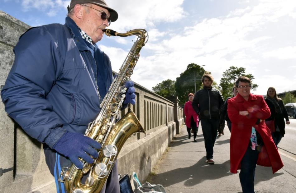 Concert-goers pass a busker while on their way to Forsyth Barr Stadium in Dunedin for Fleetwood...