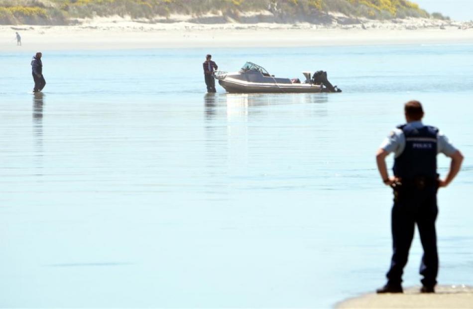 A policeman watches the pair bring their craft to shore after it capsized.