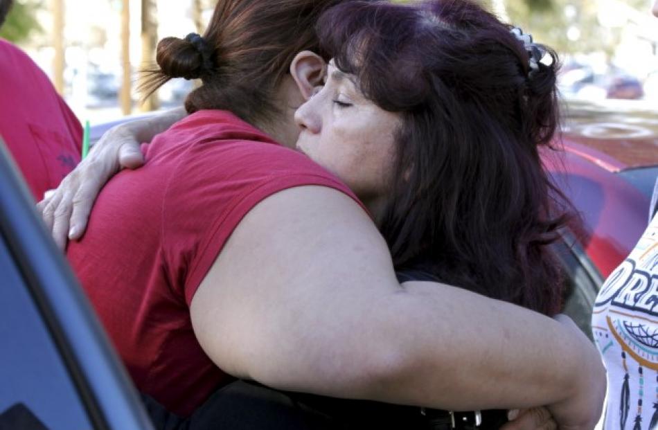 Two women hug as they wait for a relative who was not injured in the shooting.