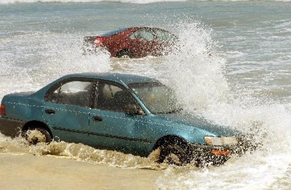 Cars are smashed by waves after becoming stuck on Tomahawk Beach.