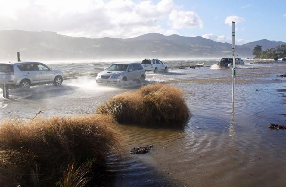 Traffic negotiates a flooded road at Macandrew Bay. Facebook/Macandrew Bay Community Page