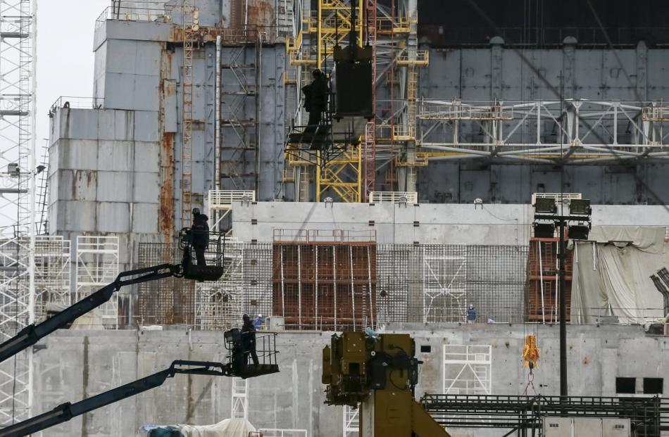 Employees work in front of the sarcophagus covering the damaged fourth reactor at the Chernobyl...