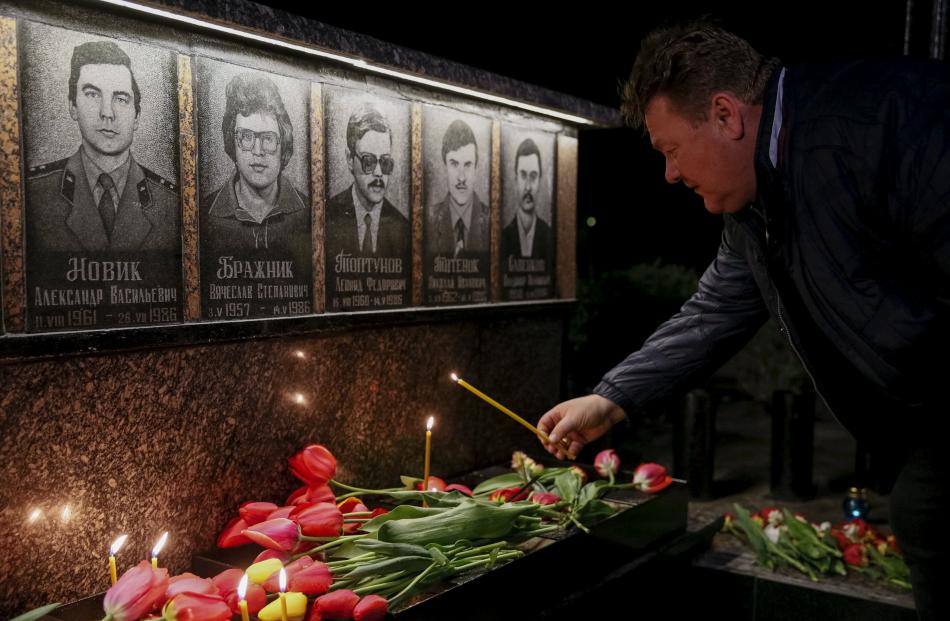 A man lights candles at a memorial dedicated to firefighters and workers who died after the...