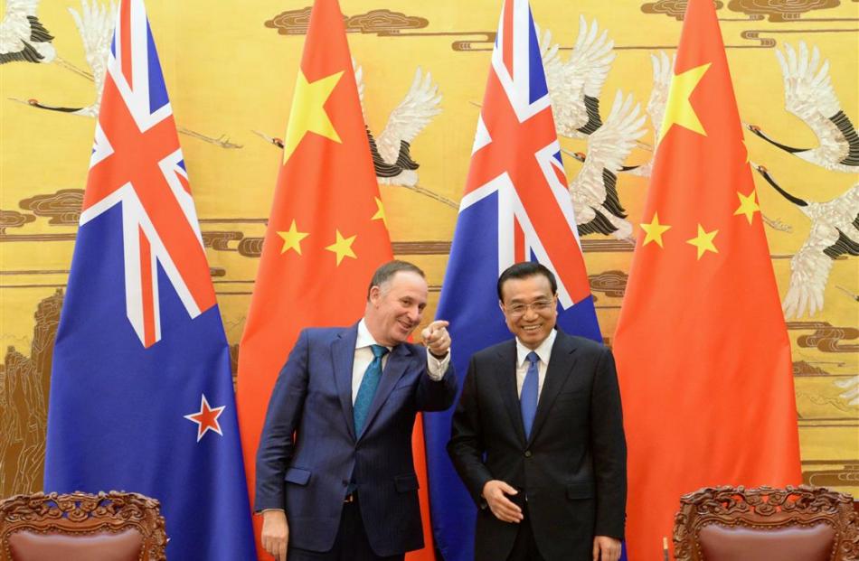 New Zealand Prime Minister John Key gestures as he shares a laugh with China’s Premier Li Keqiang...