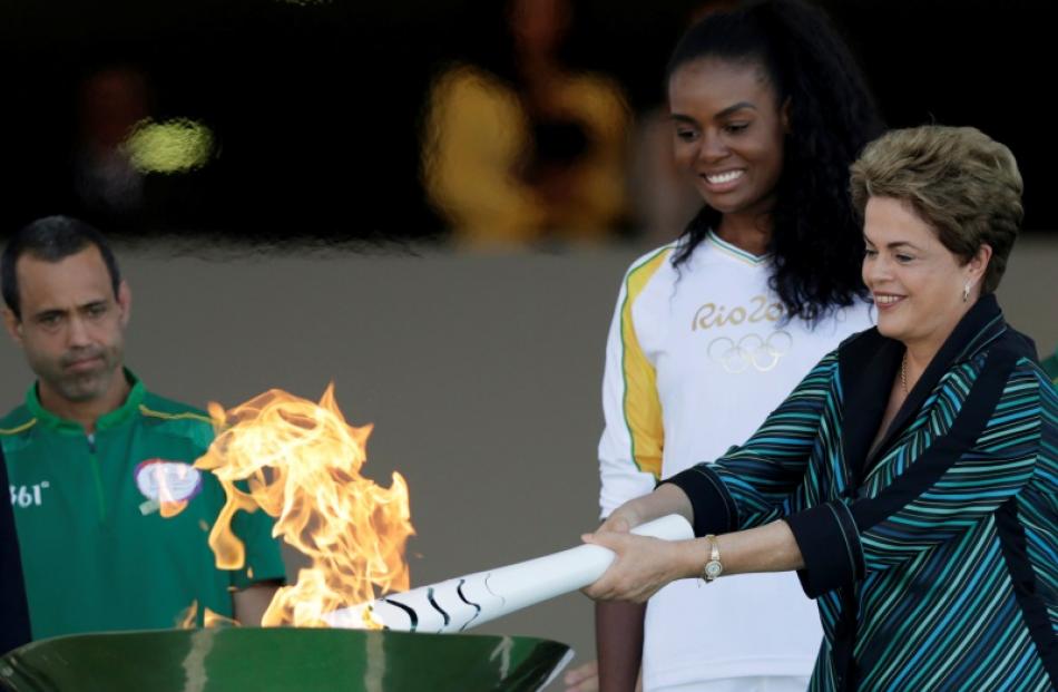 Brazil's President Dilma Rousseff (R) lights a cauldron with the Olympic Flame next to Fabiana...