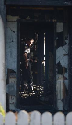 A police officer surveys the damage to the house.
