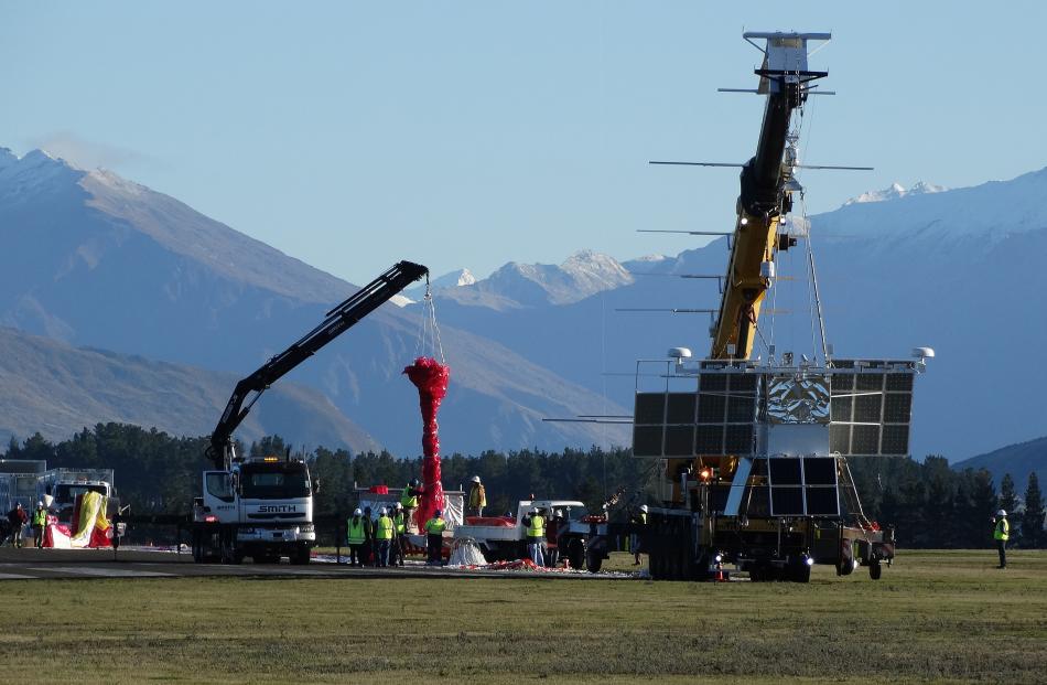 A crane (right) holds the scientific payload as the balloon is laid out behind.