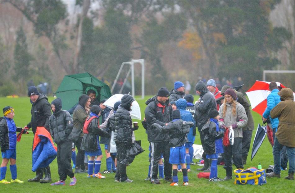 Soaked spectators try to keep up the spirits of players in wet and blustery conditions.