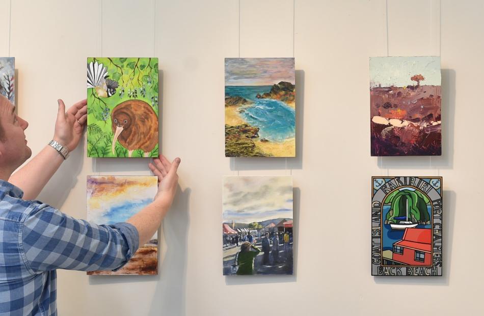 Nic Dempster hangs some of the A4 works in the Otago Art Society’s rooms at Dunedin Railway...