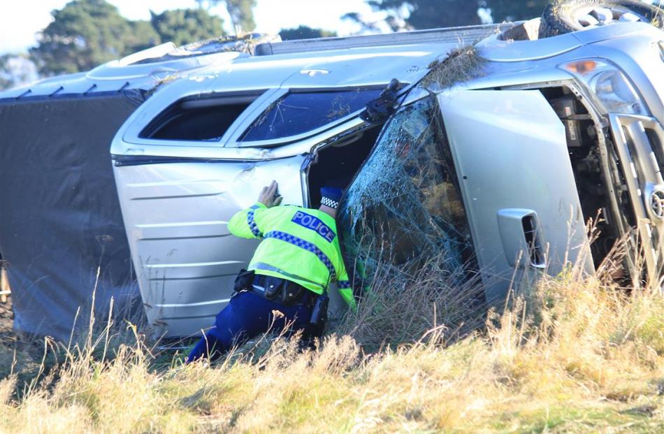 Inspecting a ute that rolled yesterday after hitting ice is Sergeant Craig Sew Hoy, of Oamaru....
