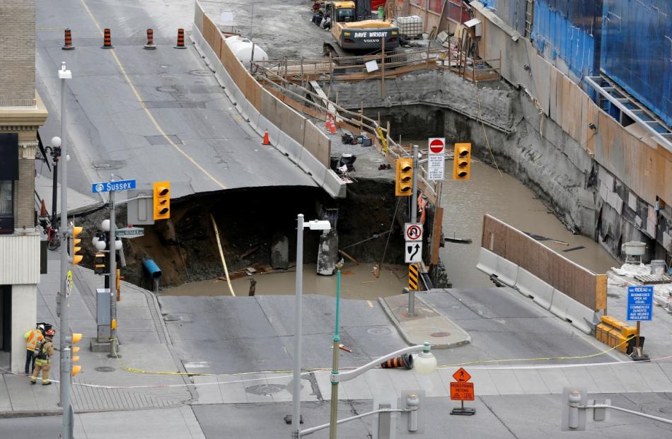 Workers look at a large sinkhole in Ottawa, Ontario, Canada. Photo by Reuters