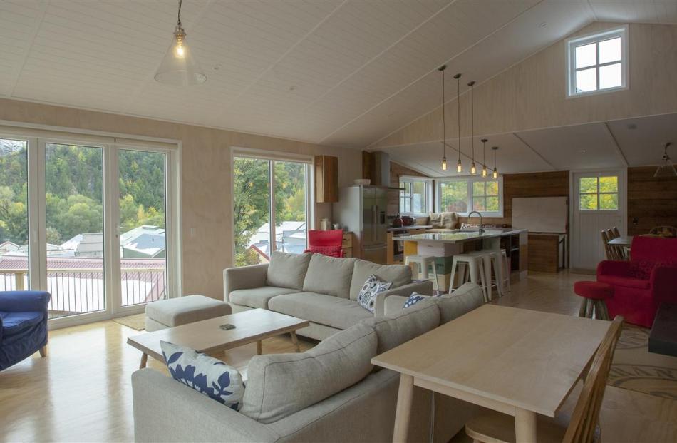 The open-plan living area has a raked ceiling, a woodburner with a waxed steel chimney and doors...