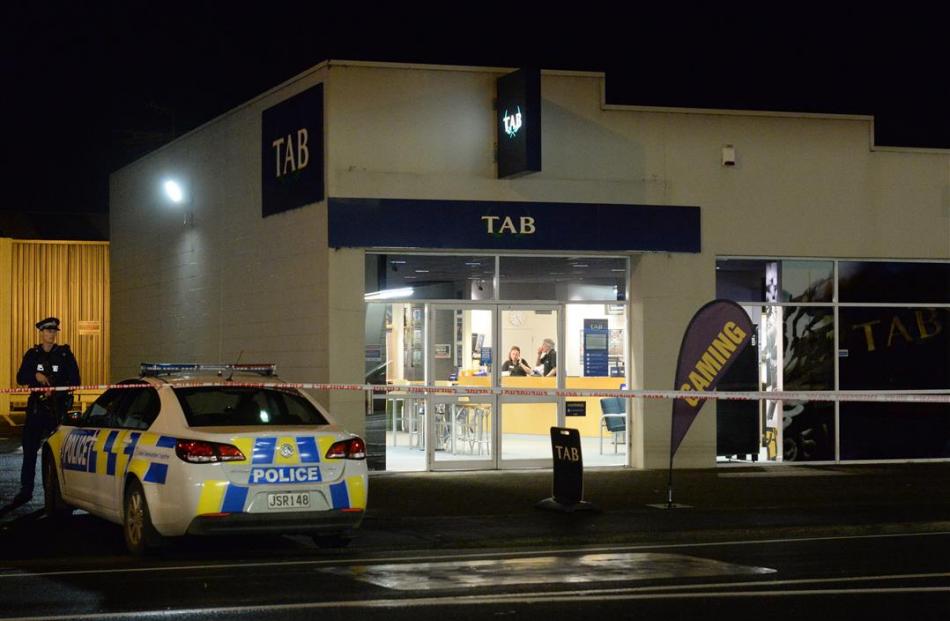 Armed police guard the scene at the TAB on Hillside Rd on Saturday after a man with a gun made...