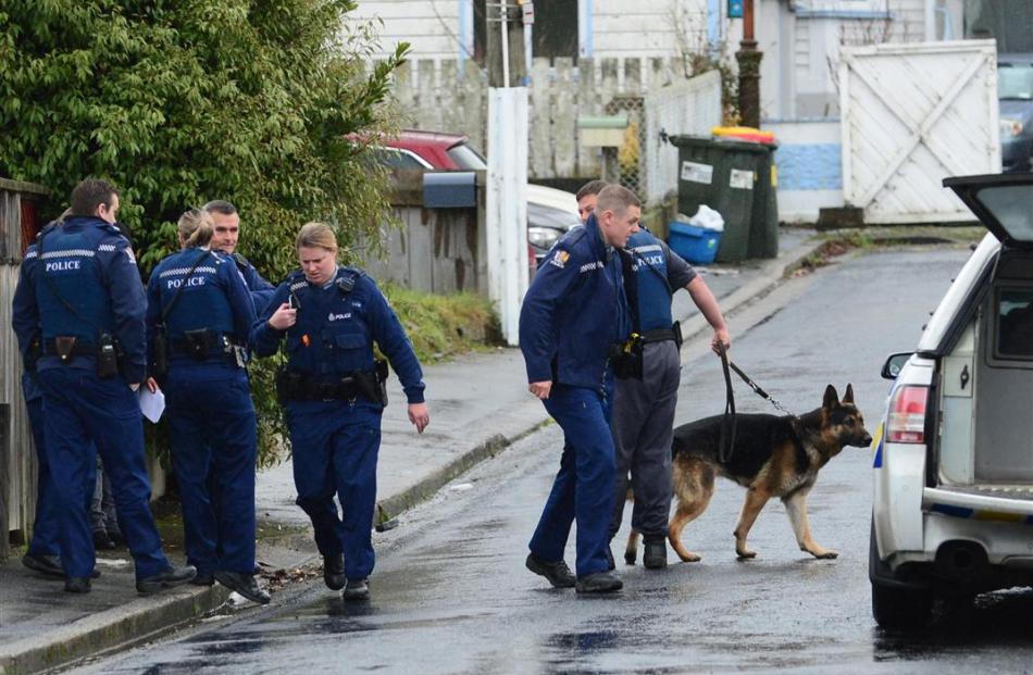Police and a dog unit prepare to enter a Cornhill St property, in Northeast Valley, yesterday....