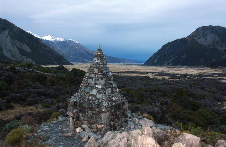 A stone cairn on a walking trail near Mount Cook Village bears plaques containing the names of...