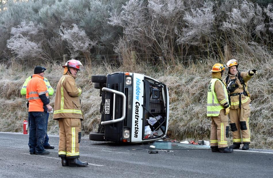 Emergency services attend to a rolled van in Three Mile Hill Rd after it hit ice in Dunedin...