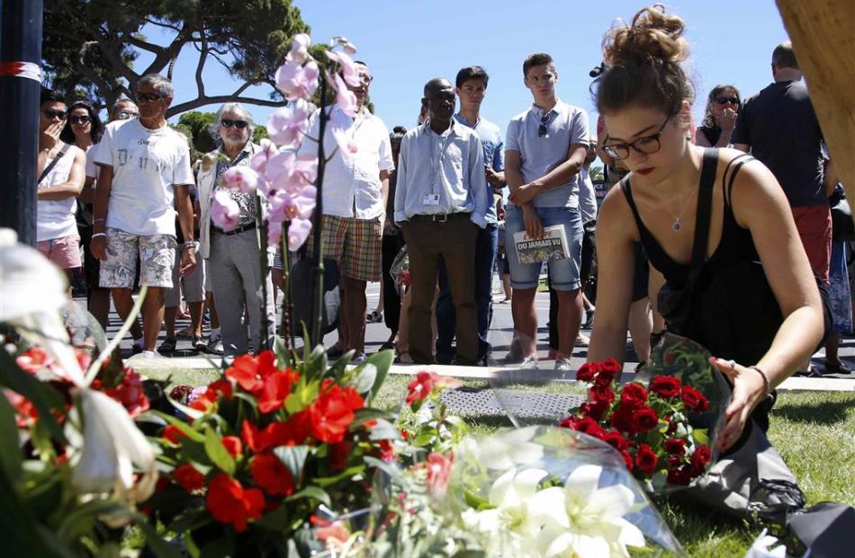 A woman places a bouquet of flowers as people pay tribute near the scene where a truck ran into a...