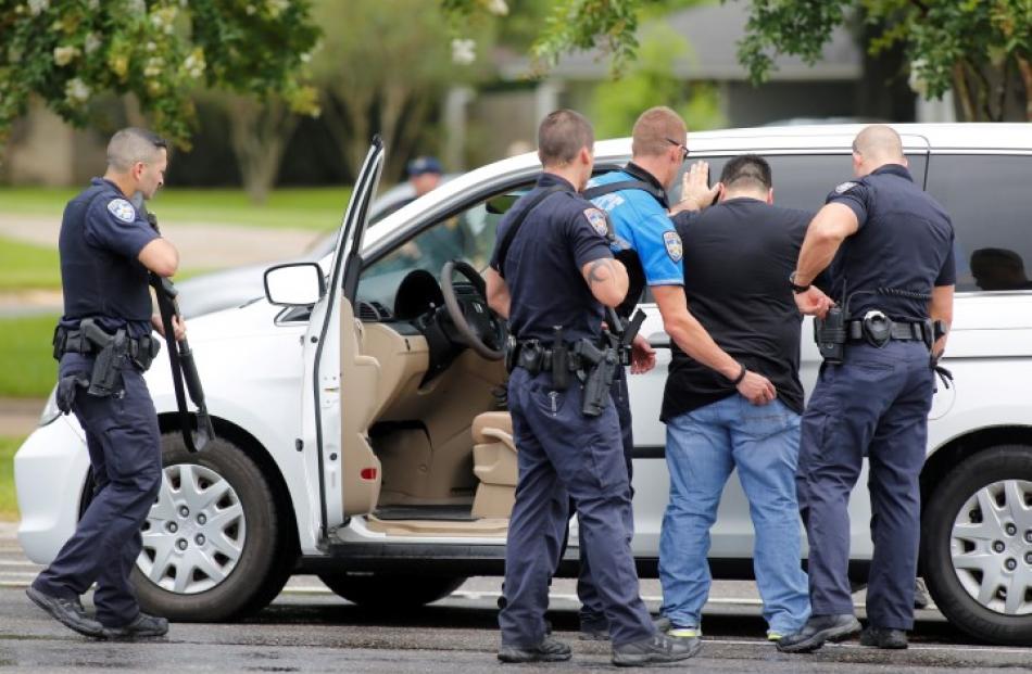 Law enforcement officers do a security check on a man in a vehicle near the site of the shooting....