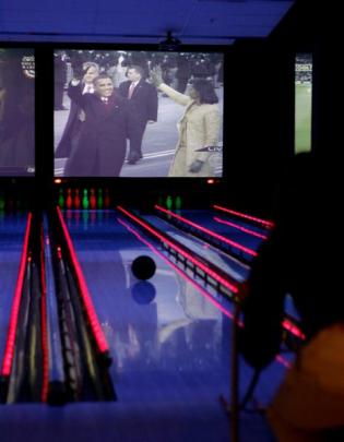 A bowler bowls at Strike bowling alley in Cupertino, California, as they watch President Barack...