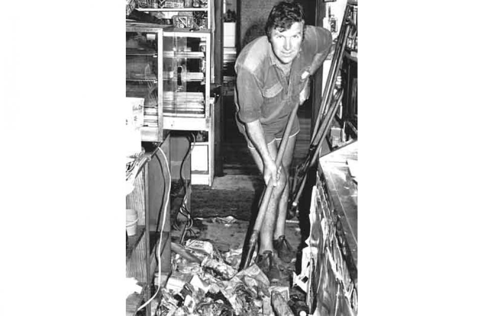 Graham Molloy of the Collingwood Food Centre scoops up debris from his shop floor. He took away...