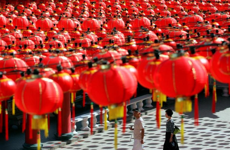 Tourists walk underneath the Chinese traditional lanterns on display at a temple in Kuala Lumpur,...