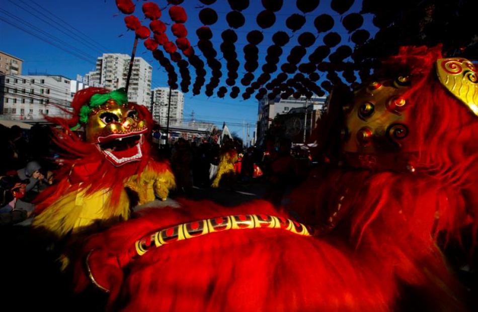 Dancers dressed in traditional Chinese costumes perform a lion dance at the opening ceremony of a...