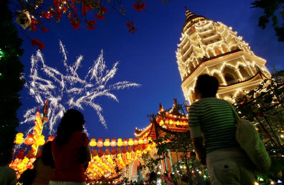 Visitors look at fireworks during the Chinese New Year light up ceremony at Kek Lok Si Buddhist...