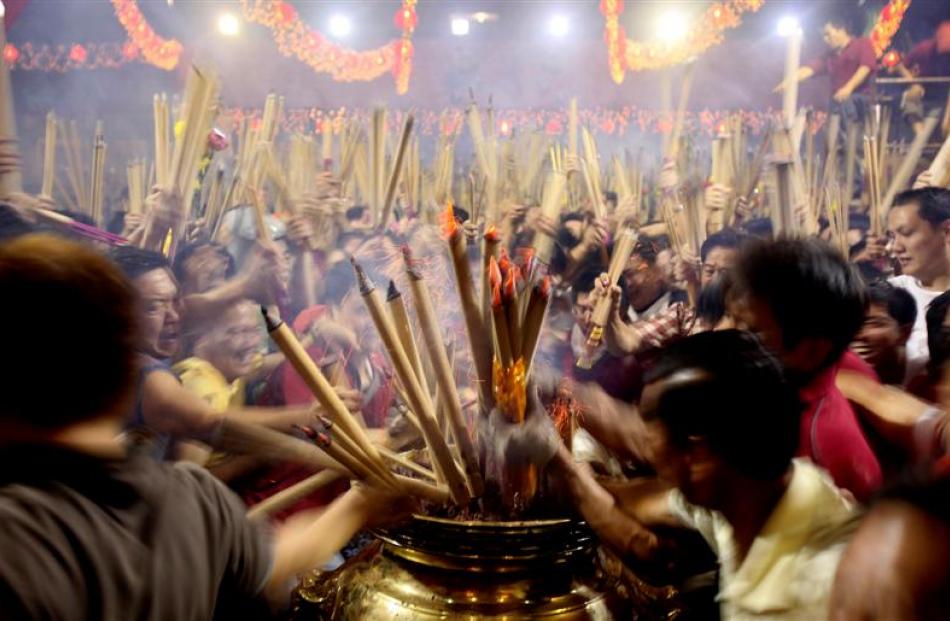Buddhists rush to stick incense sticks in an urn at a local Chinese Buddhist temple in Singapore....