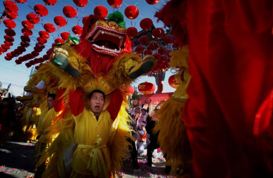 Dancers dressed in traditional Chinese costumes perform a lion dance at the opening ceremony of a...