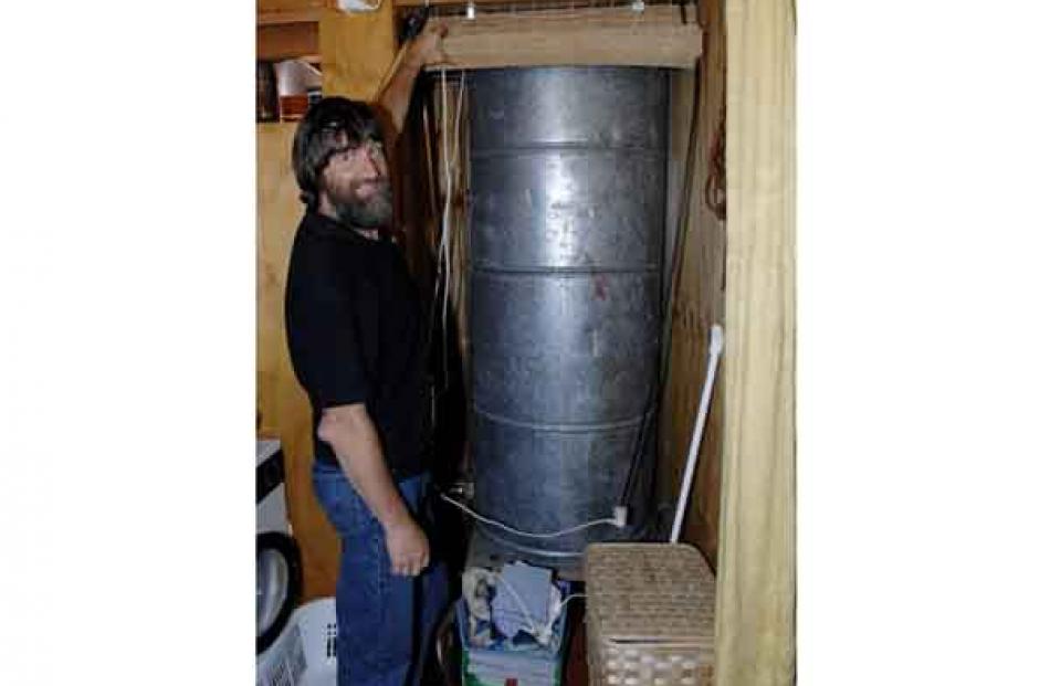 Mr Grimwood shows off the huge ex-industrial hot water cylinder in the bathroom.