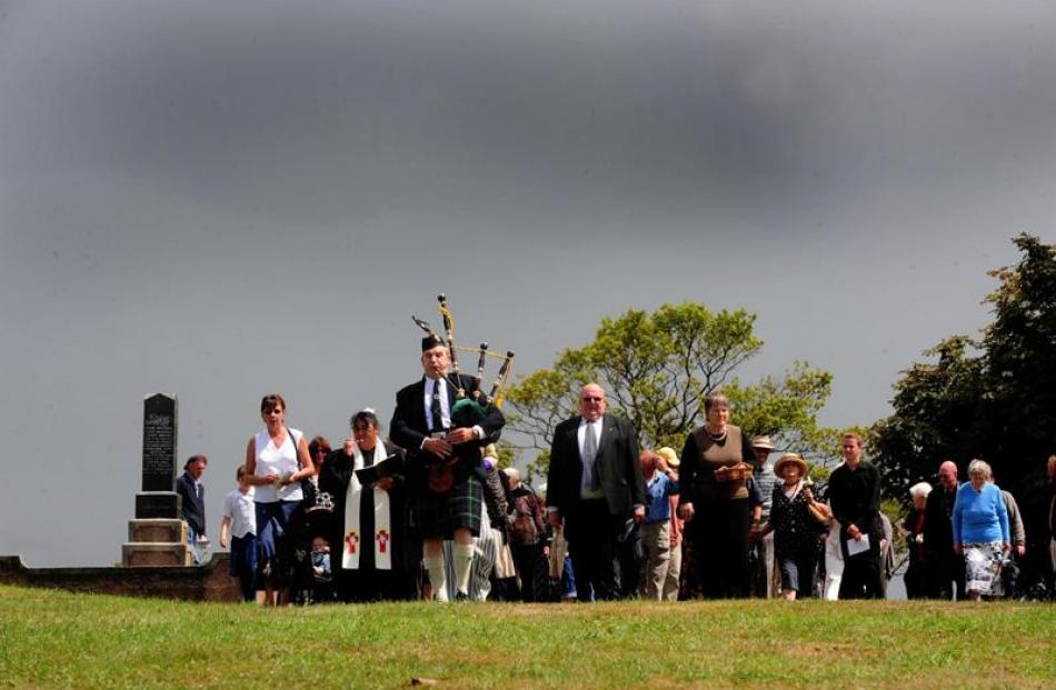 Bagpiper Max Wells leads family and guests to the grave.