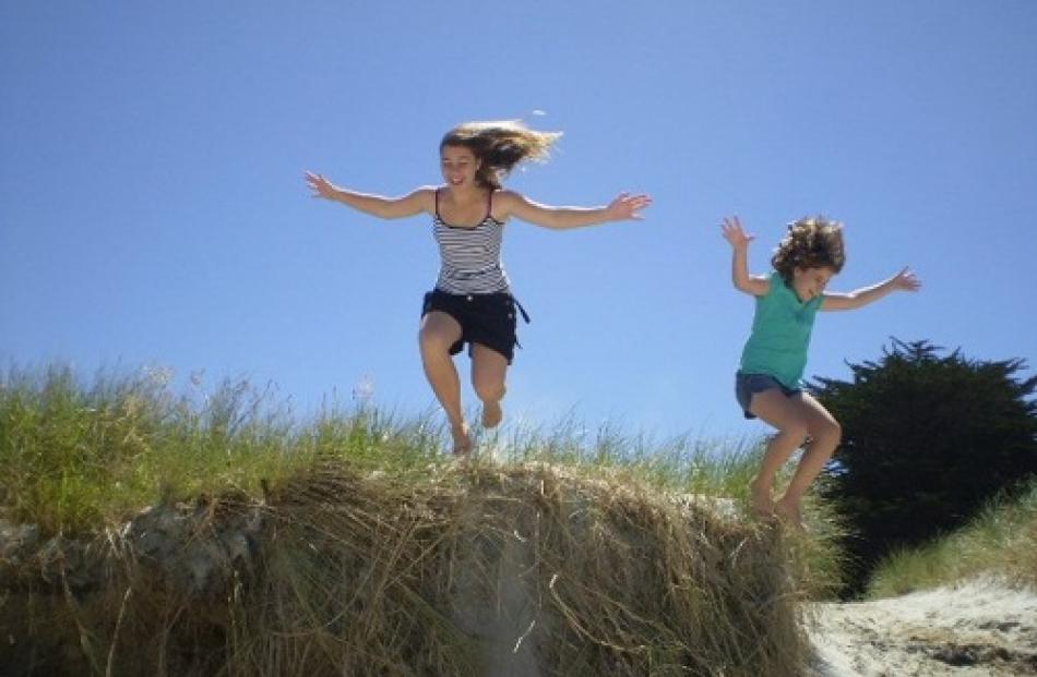 Brittney (12) and Ellie Englefield (9), of Brisbane, have a bal jumping off sand dunes south of...