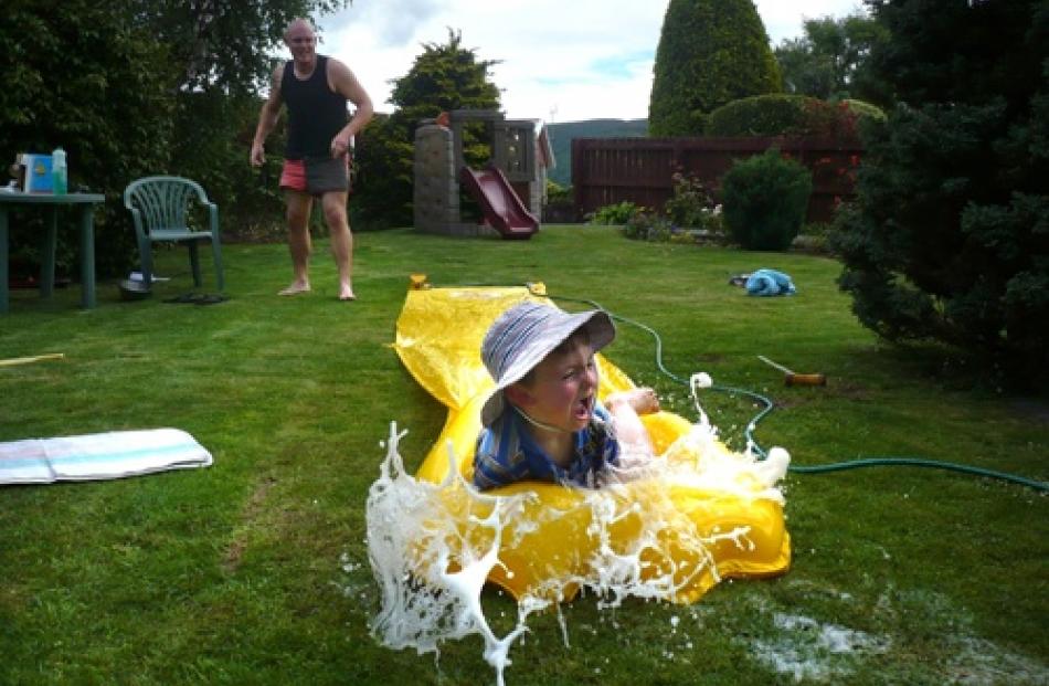 Fergus Hepburn (3) takes a ride down the water slide, with a helping push from uncle Matt...