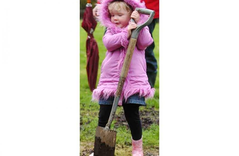 Olivia Adie (2) helps her father Bryce plant a native tree to mark the birth of her baby sister...