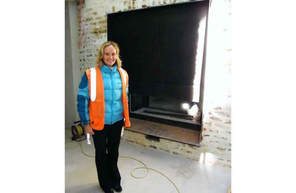 Westwood Group Holdings marketing manager Jo Smith stands beside the large, gas-powered fireplace...