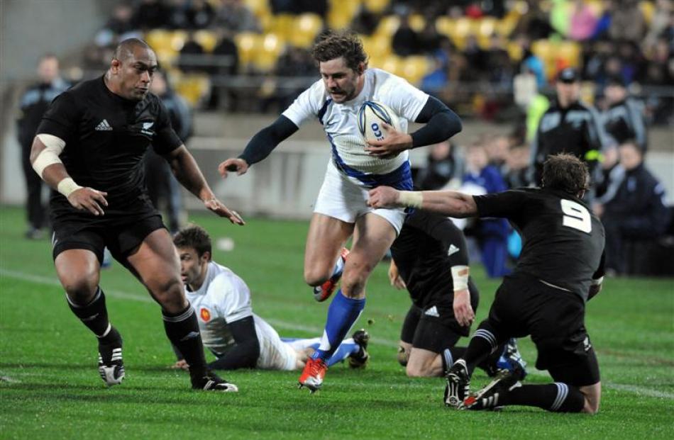 France's Cedric Heymans, centre, runs between New Zealand's Neemia Tialata, left and Jimmy Cowan....