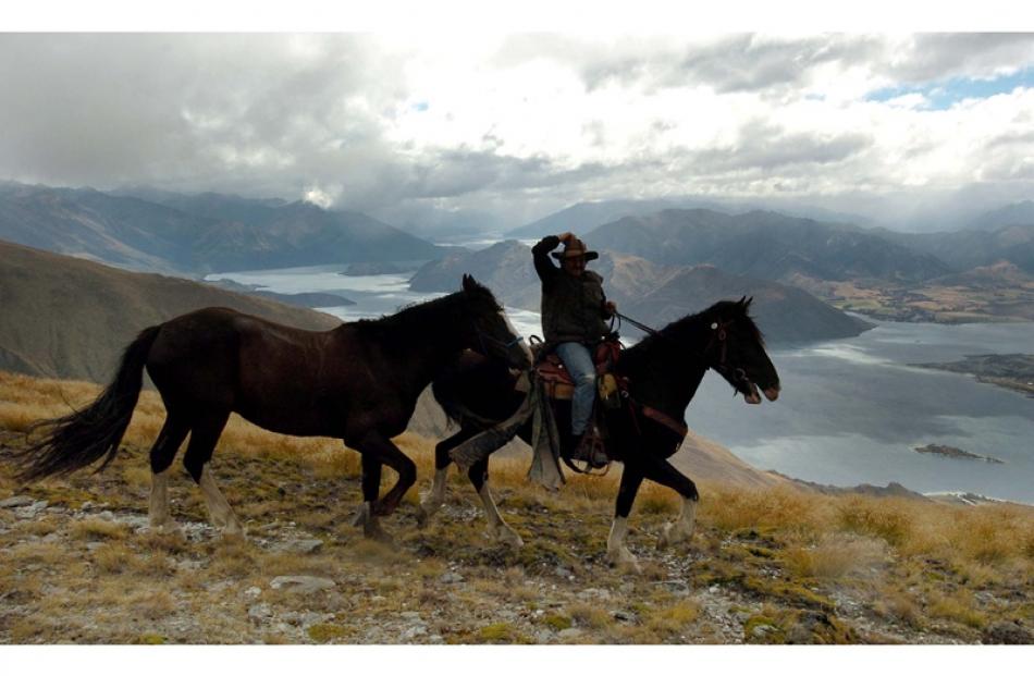 Raymond Moynahan from Christchurch hangs onto his hat as he decends Mt Alpha above Lake Wanaka to...