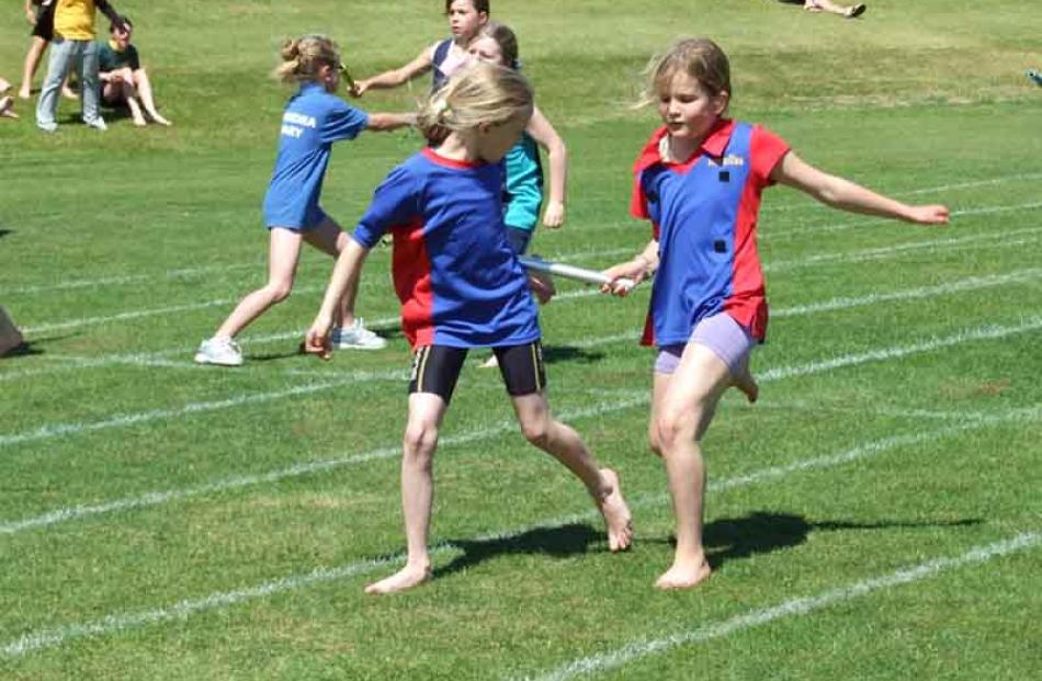 Great exchange . . . Sofie Arhanic (8,left) is handed the baton by her Arrowtown Primary  team...