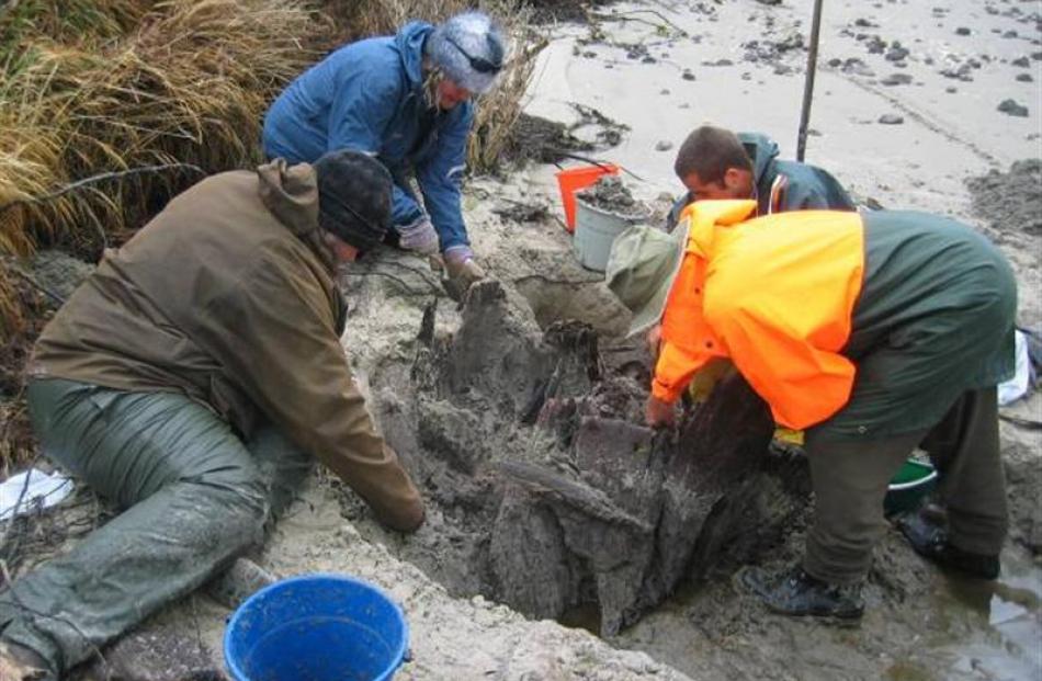 People work to excavate the wooden object.