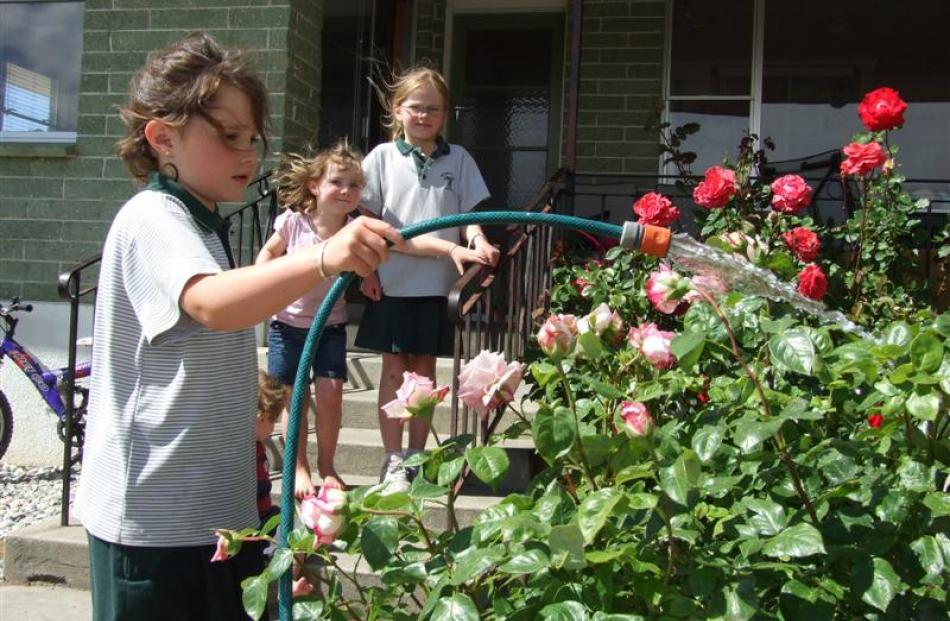 Isabella Herbert (7) waters the roses at her Alexandra home, watched by sisters Kimberley (9,...