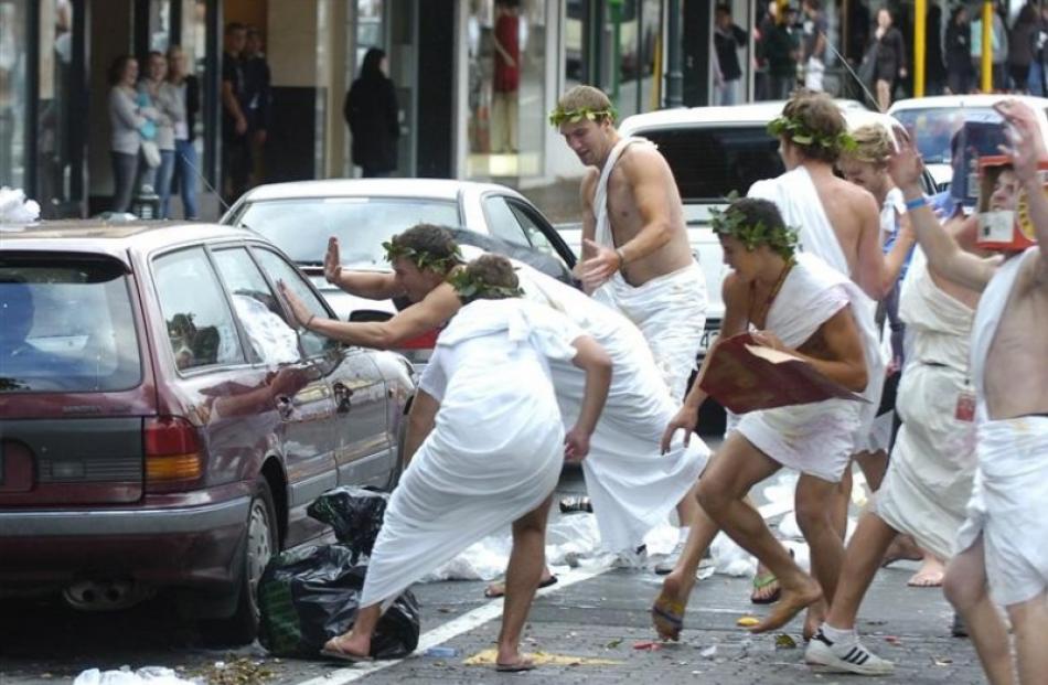 A car is engulfed by toga-clad students.